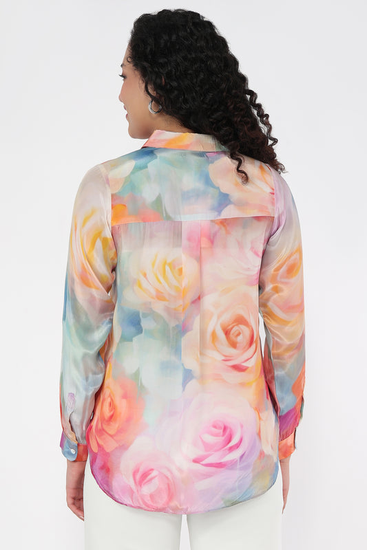 Woman wearing a colorful rose-patterned blouse against a white background