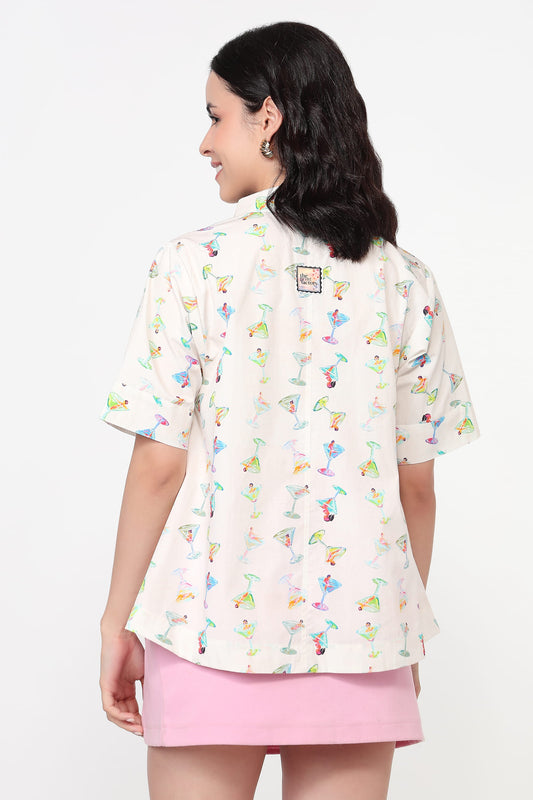Woman wearing a white blouse with colorful patterns and a pink skirt on a white background