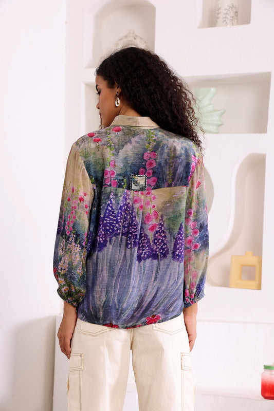 Woman wearing a colorful floral blouse in a minimal indoor setting