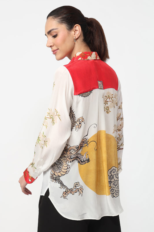 Woman wearing a white shirt with red, yellow, and black patterns on a white background