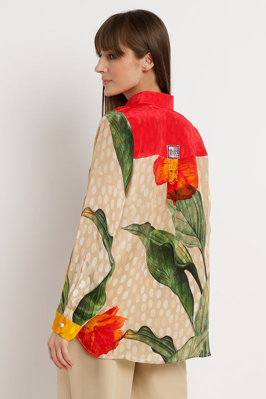 Woman wearing a colorful floral jacket with a red shirt underneath on a white background