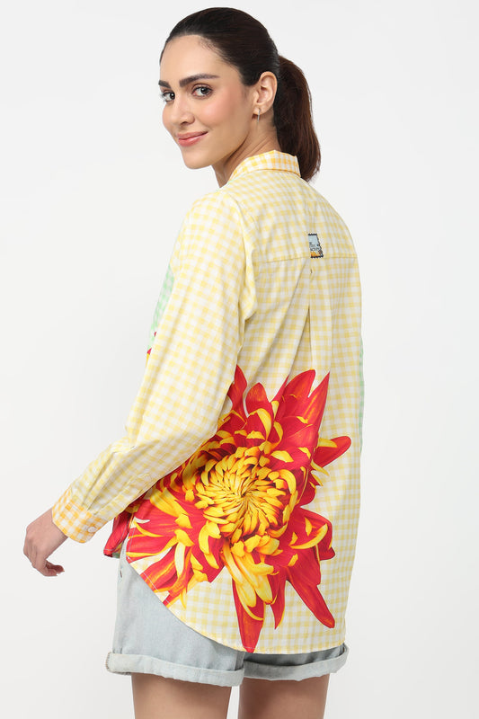 Woman wearing a yellow checkered shirt with a red floral design on a white background