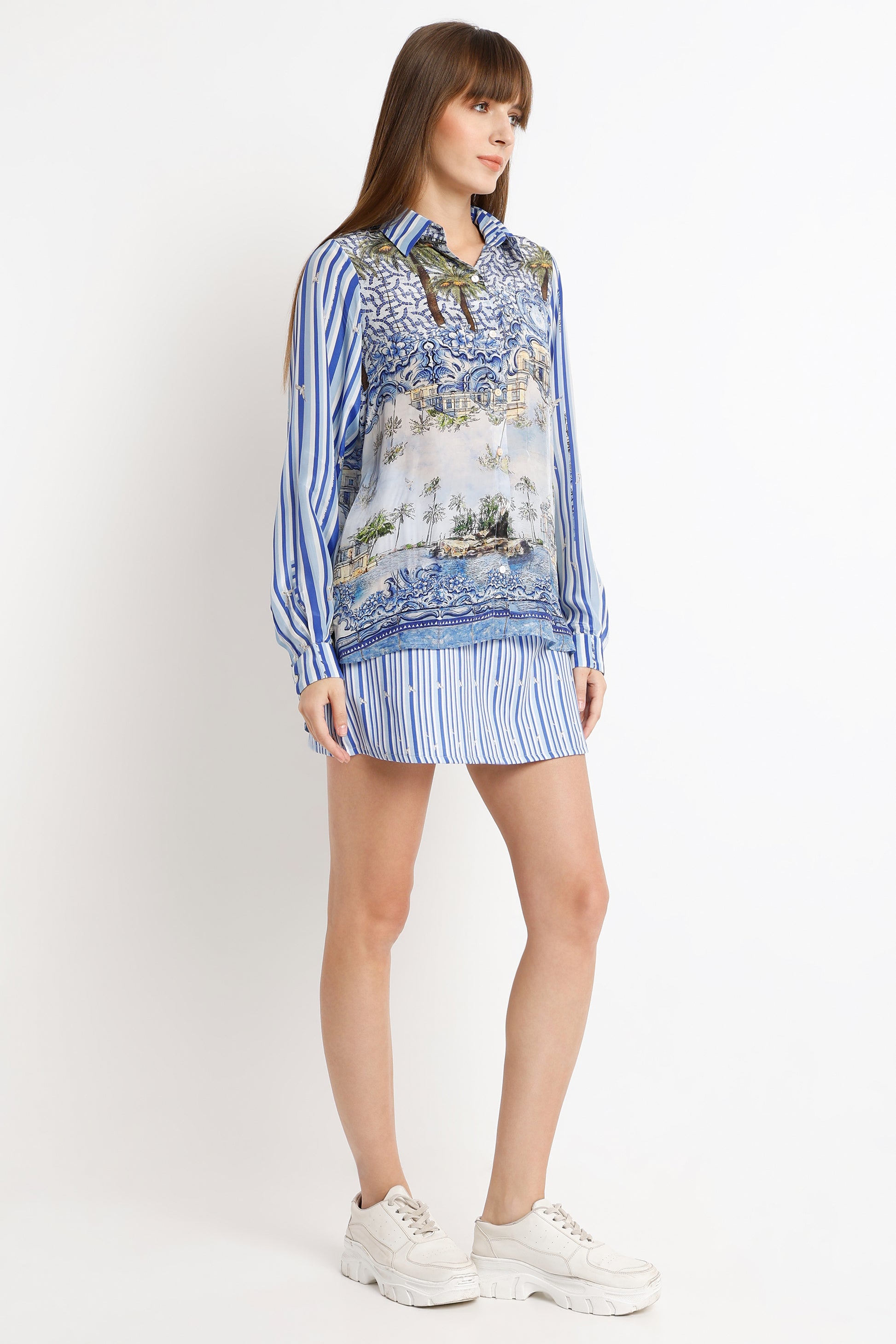 Woman wearing a patterned blouse and striped skirt on a white background