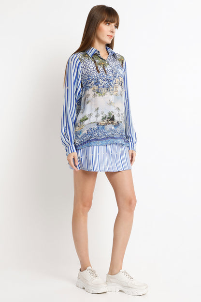 Woman wearing a patterned blouse and striped skirt on a white background