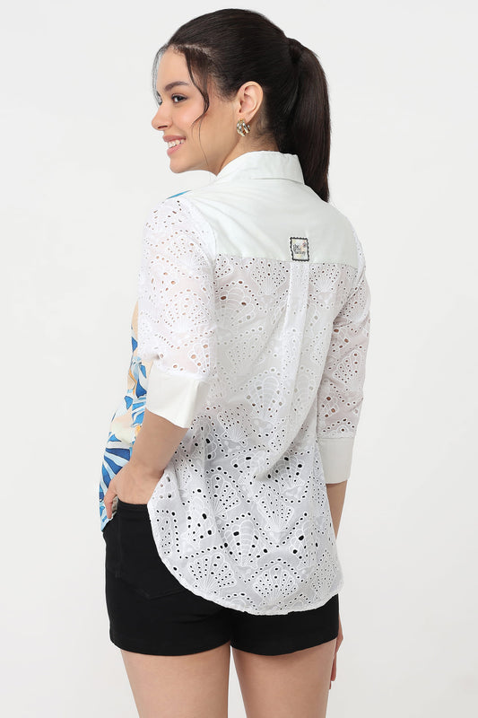 A woman shown from the back wearing a white eyelet button-up shirt with three-quarter sleeves and black shorts, against a plain white studio background.