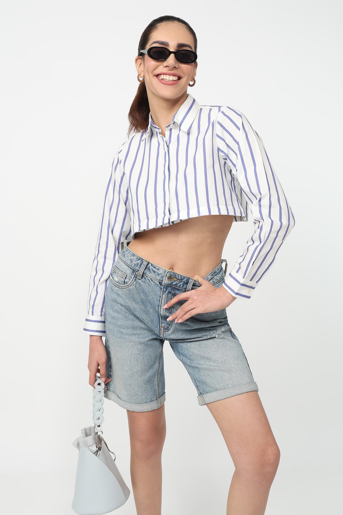Woman wearing a striped shirt and denim shorts on a white background