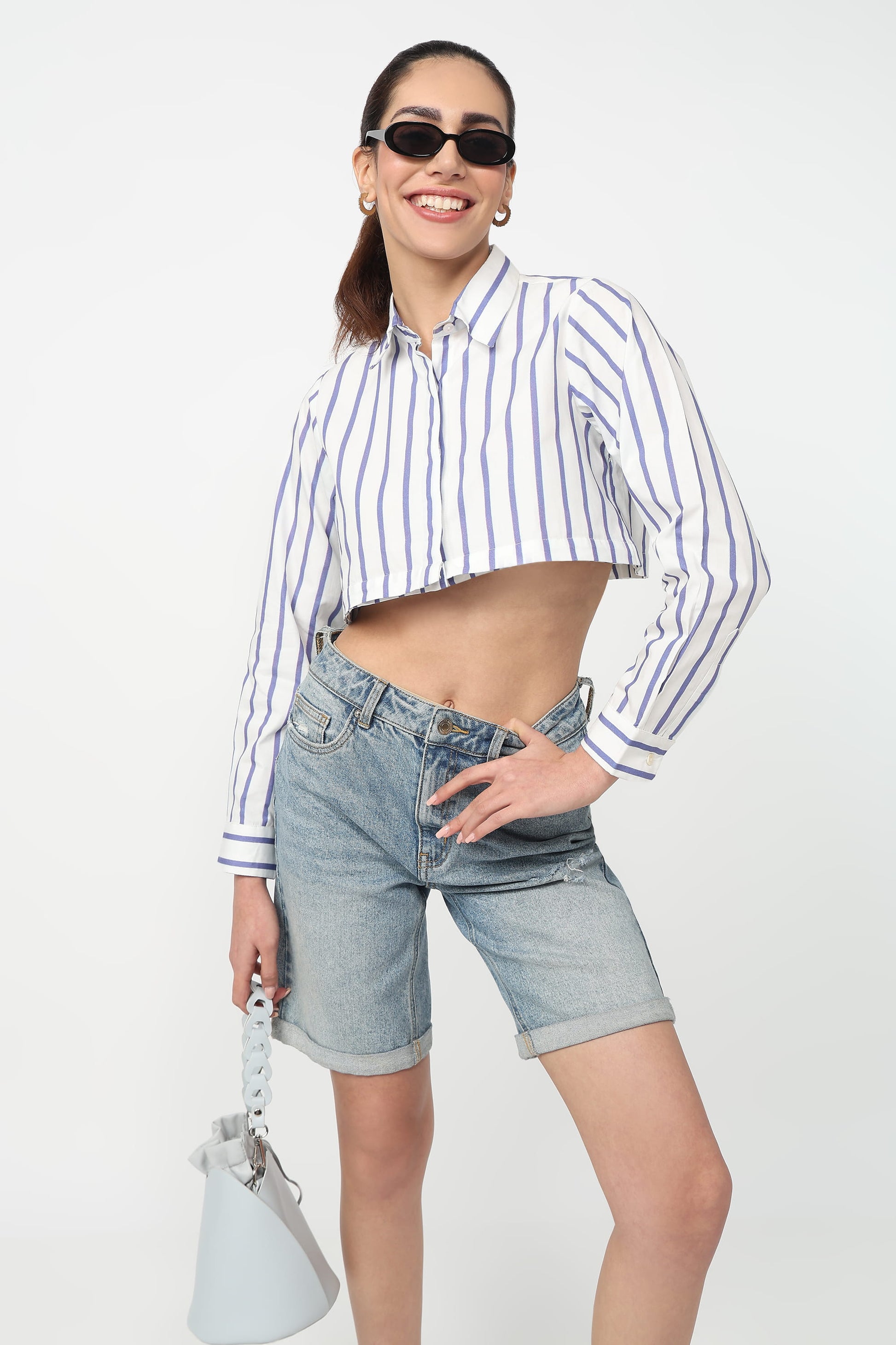 Woman wearing a striped shirt and denim shorts on a white background
