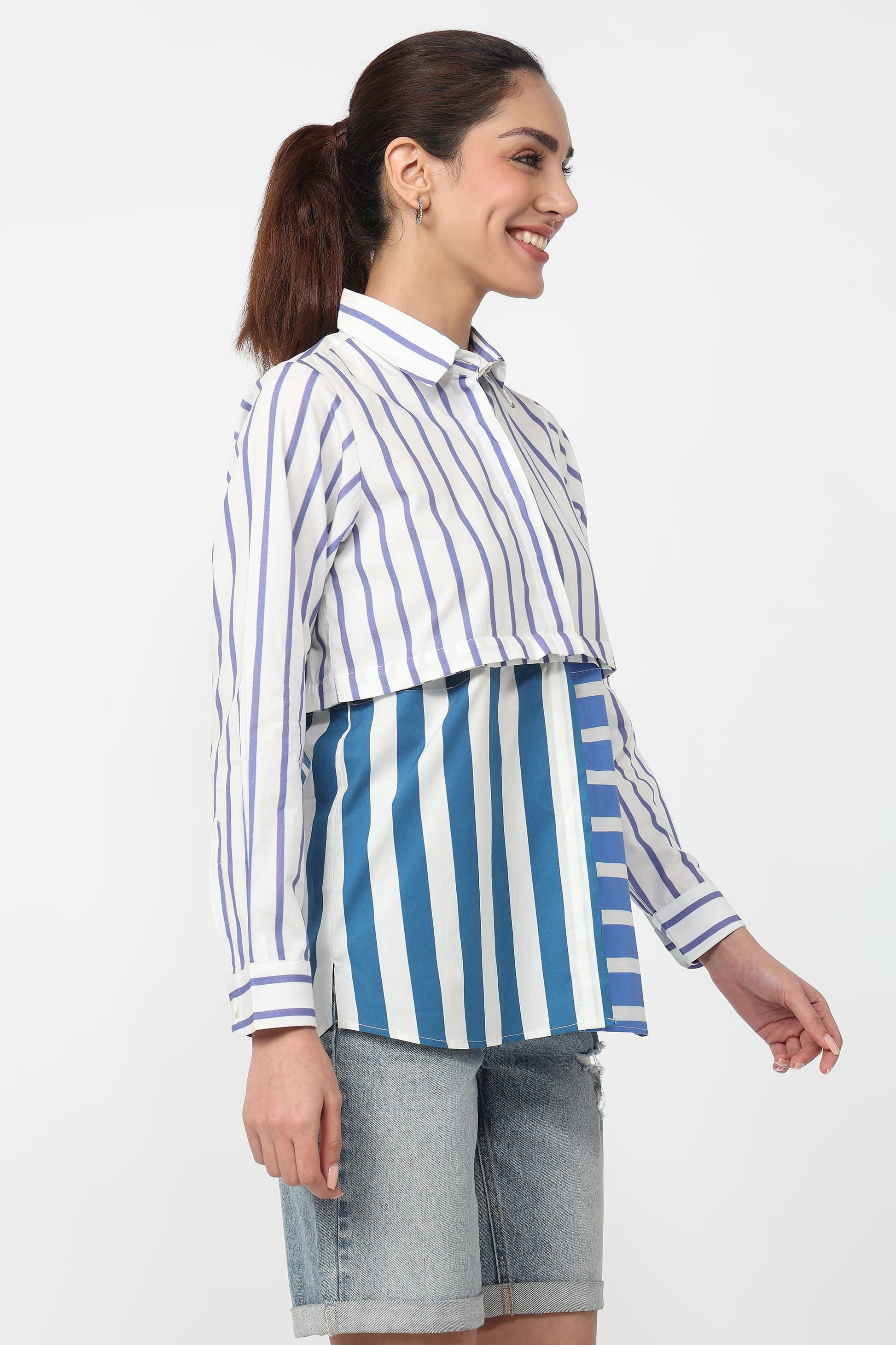 Woman wearing a blue and white striped shirt with denim shorts on a white background