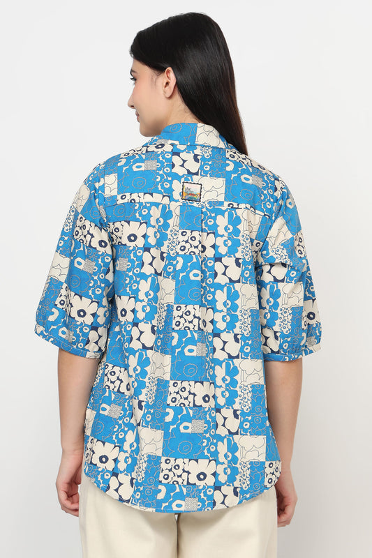 Person wearing a blue and white patterned shirt on a plain background