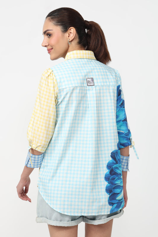 Woman wearing a light blue checkered shirt with floral sleeves on a white background