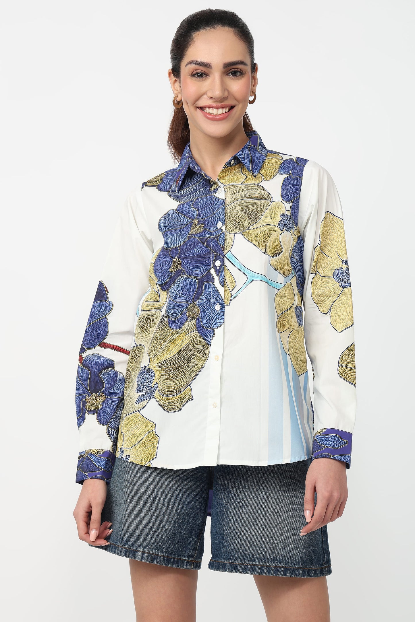 Woman wearing a floral shirt with denim shorts on a white background