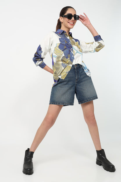 Woman wearing a patterned shirt, denim shorts, and black boots on a white background