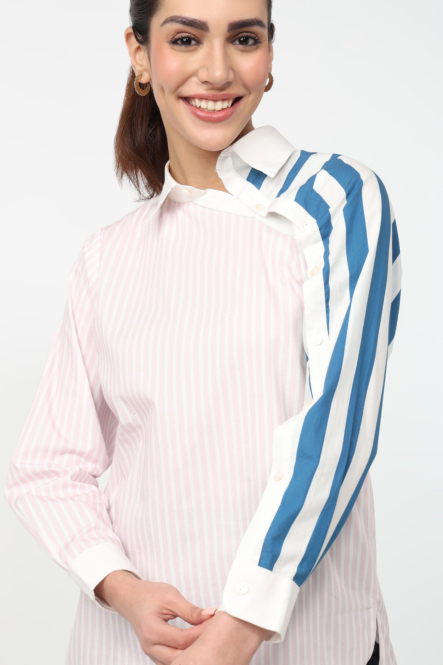 Woman wearing a white and pink striped shirt with blue and white striped sleeves on a white background