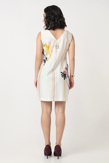 A woman wearing a sleeveless V-neck dress with a colourful floral print and vertical stripes on the bodice and, paired with black heels, against a plain light grey background.