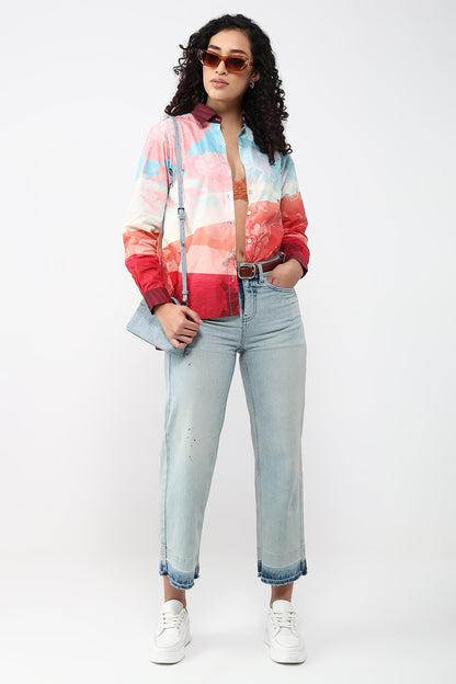 Woman wearing a colorful jacket, light blue jeans, and white sneakers on a white background