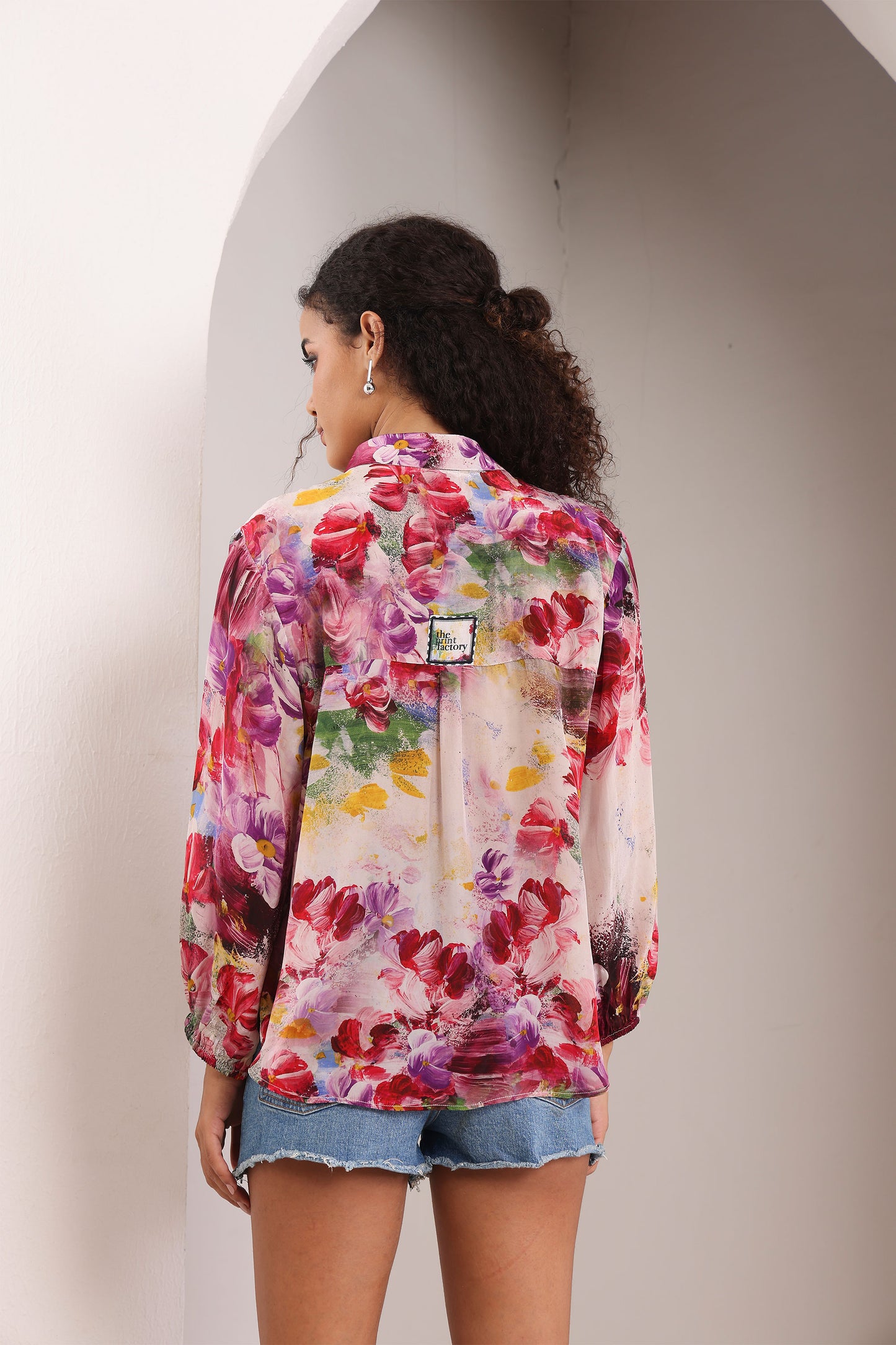 Woman wearing a colorful floral jacket against a neutral background