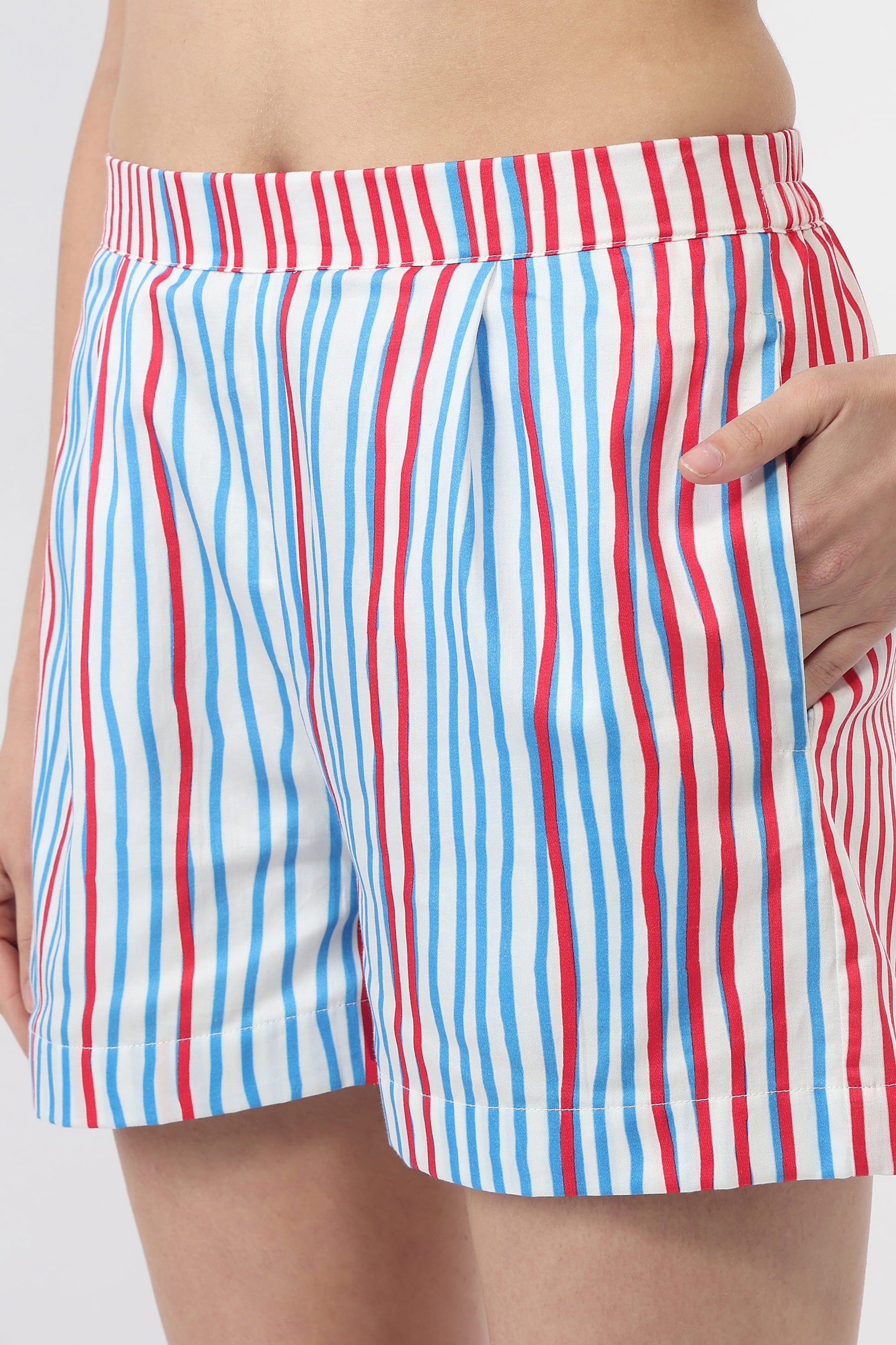 A close-up of a person wearing striped shorts with vertical red, white, and blue stripes, showing the side pocket and hand.