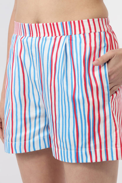 A close-up of a person wearing striped shorts with vertical red, white, and blue stripes, showing the side pocket and hand.