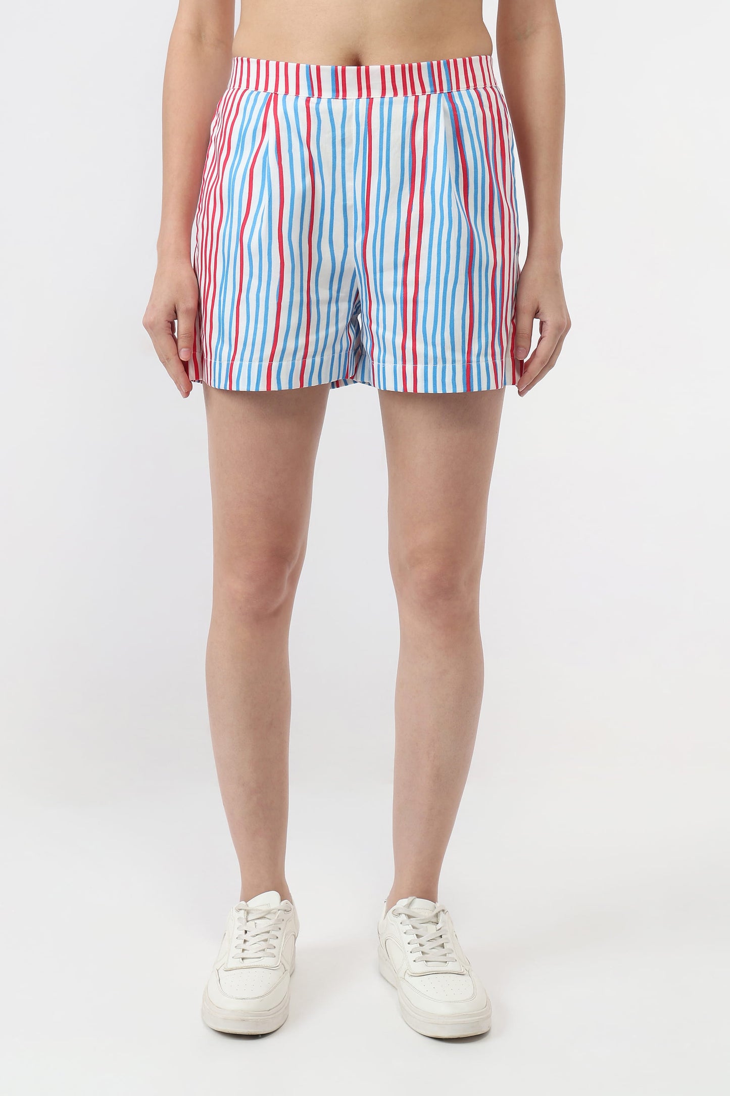 A model wearing striped boxer shorts with vertical red, blue, and white stripes, paired with white sneakers, shown from the waist down on a light gray studio background.
