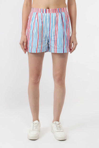 A model wearing striped boxer shorts with vertical red, blue, and white stripes, paired with white sneakers, shown from the waist down on a light gray studio background.