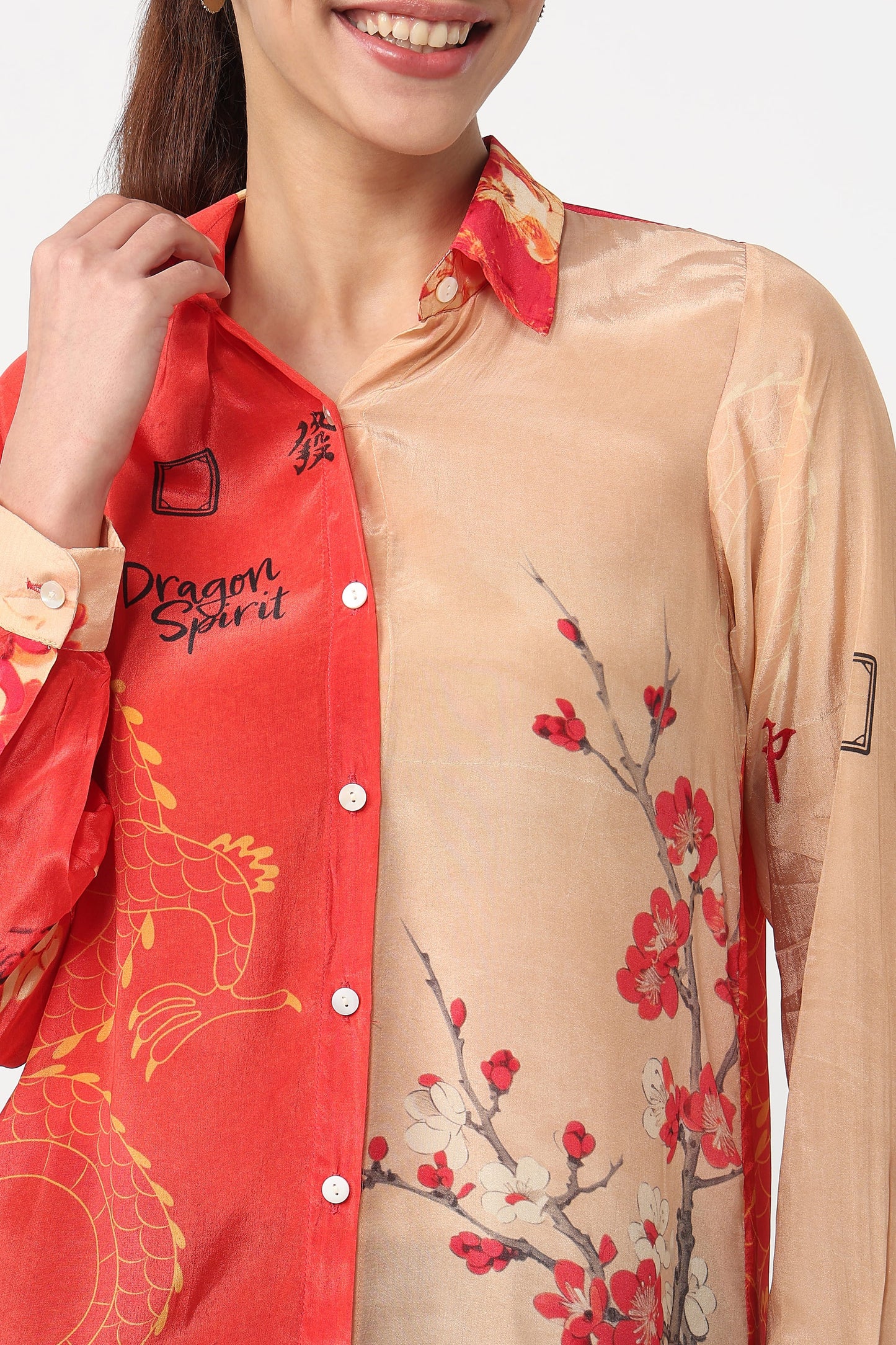 Woman wearing a red and beige shirt with floral and dragon designs.