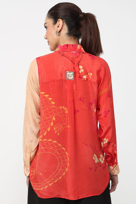 Person wearing a red floral and dragon design shirt on a white background