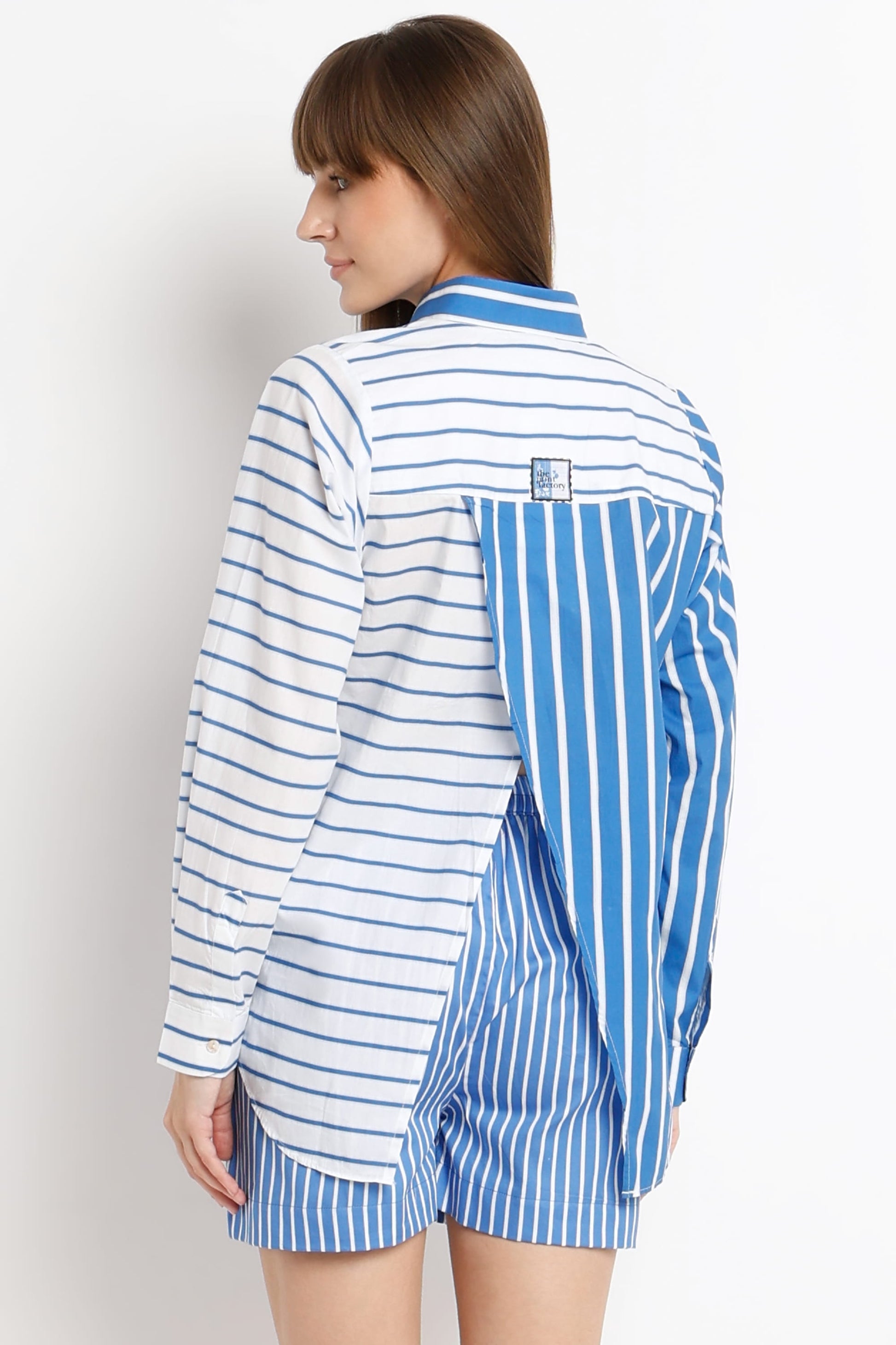 A model shown from the back wearing a blue and white striped shirt and matching shorts, set against a plain light gray studio background.