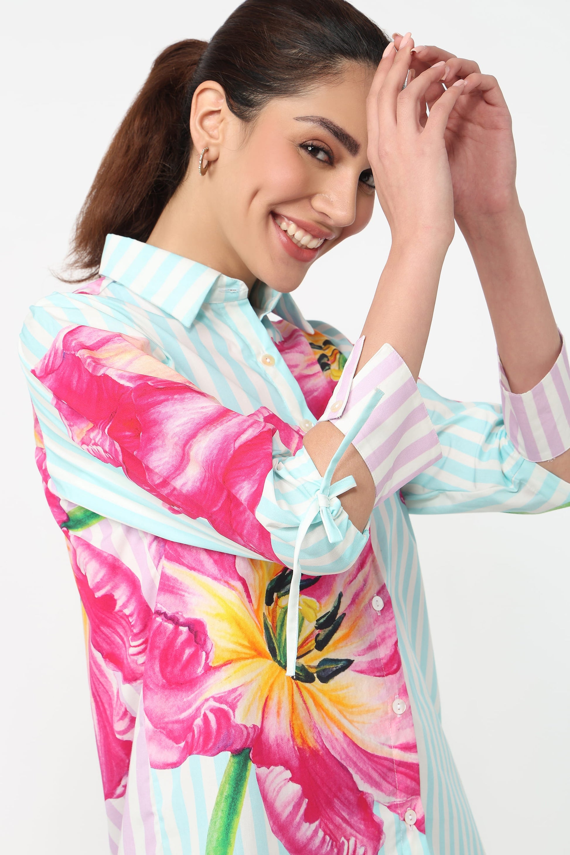 Woman wearing a colorful floral and striped shirt on a white background