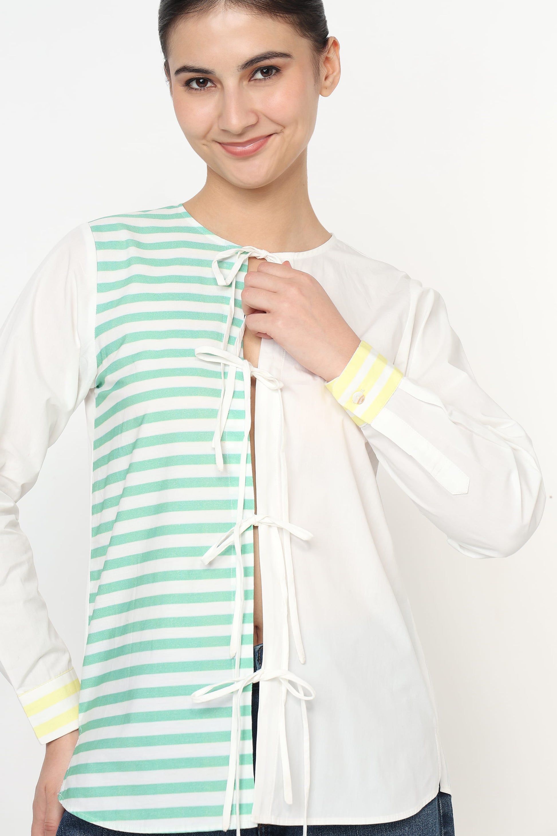 Woman wearing a white jacket with a green and white striped panel on a white background