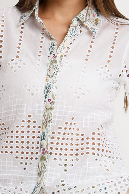White eyelet button-up shirt with a floral printed placket and collar, shown on a model.