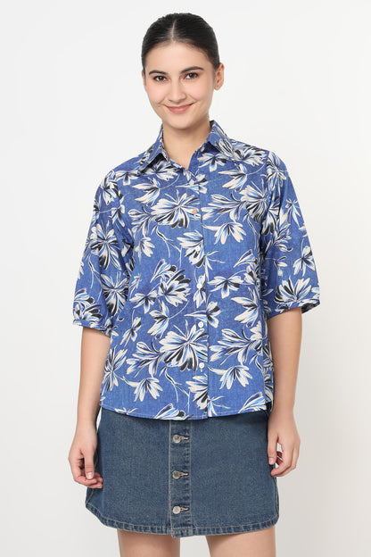 Woman wearing a blue floral shirt and denim skirt on a white background