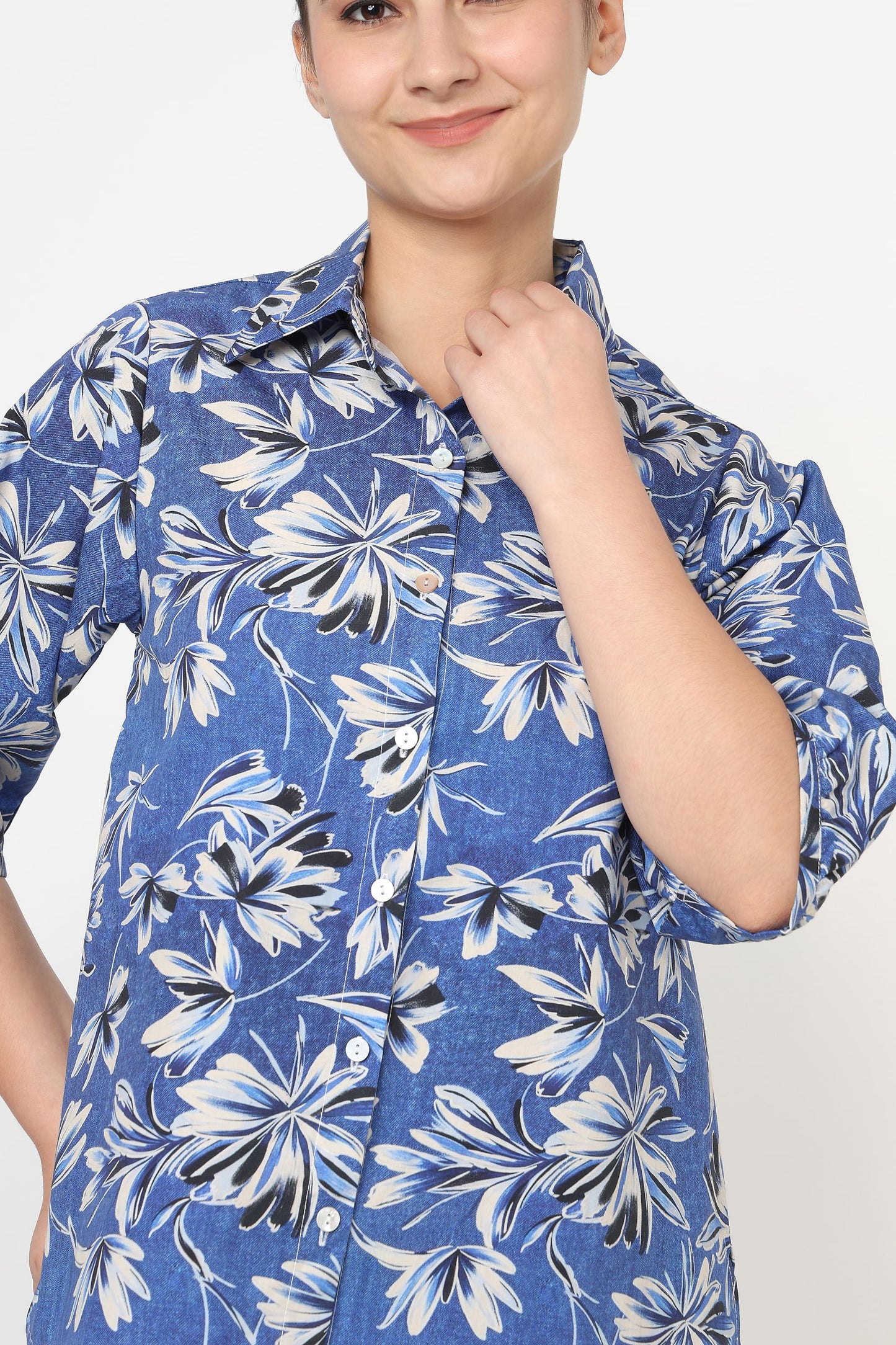 Person wearing a blue floral patterned shirt against a white background