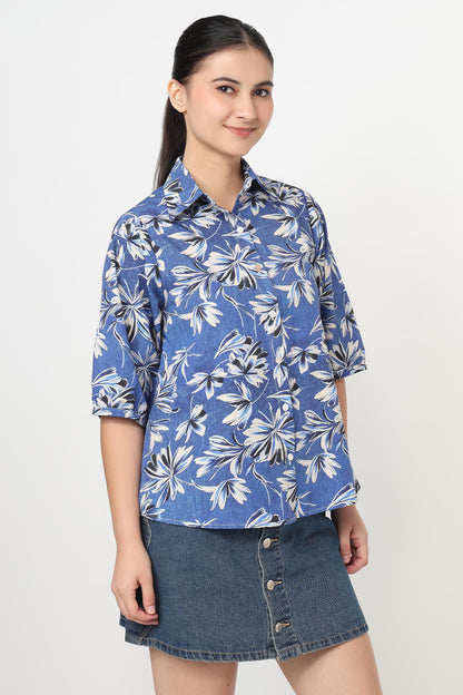 Woman wearing a blue floral shirt and denim skirt on a white background