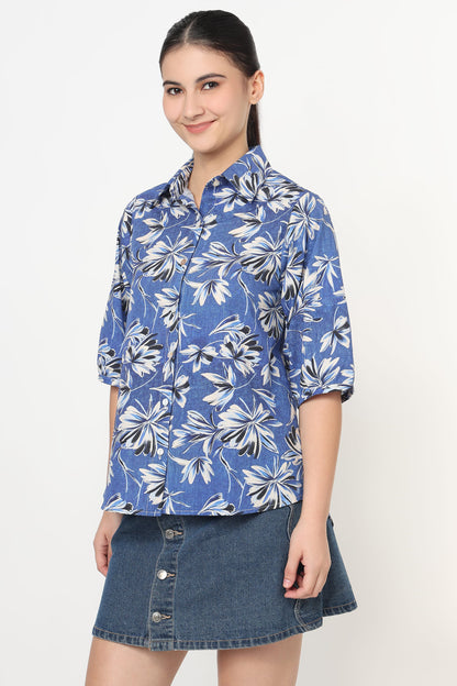 Woman wearing a blue floral shirt and denim skirt on a white background