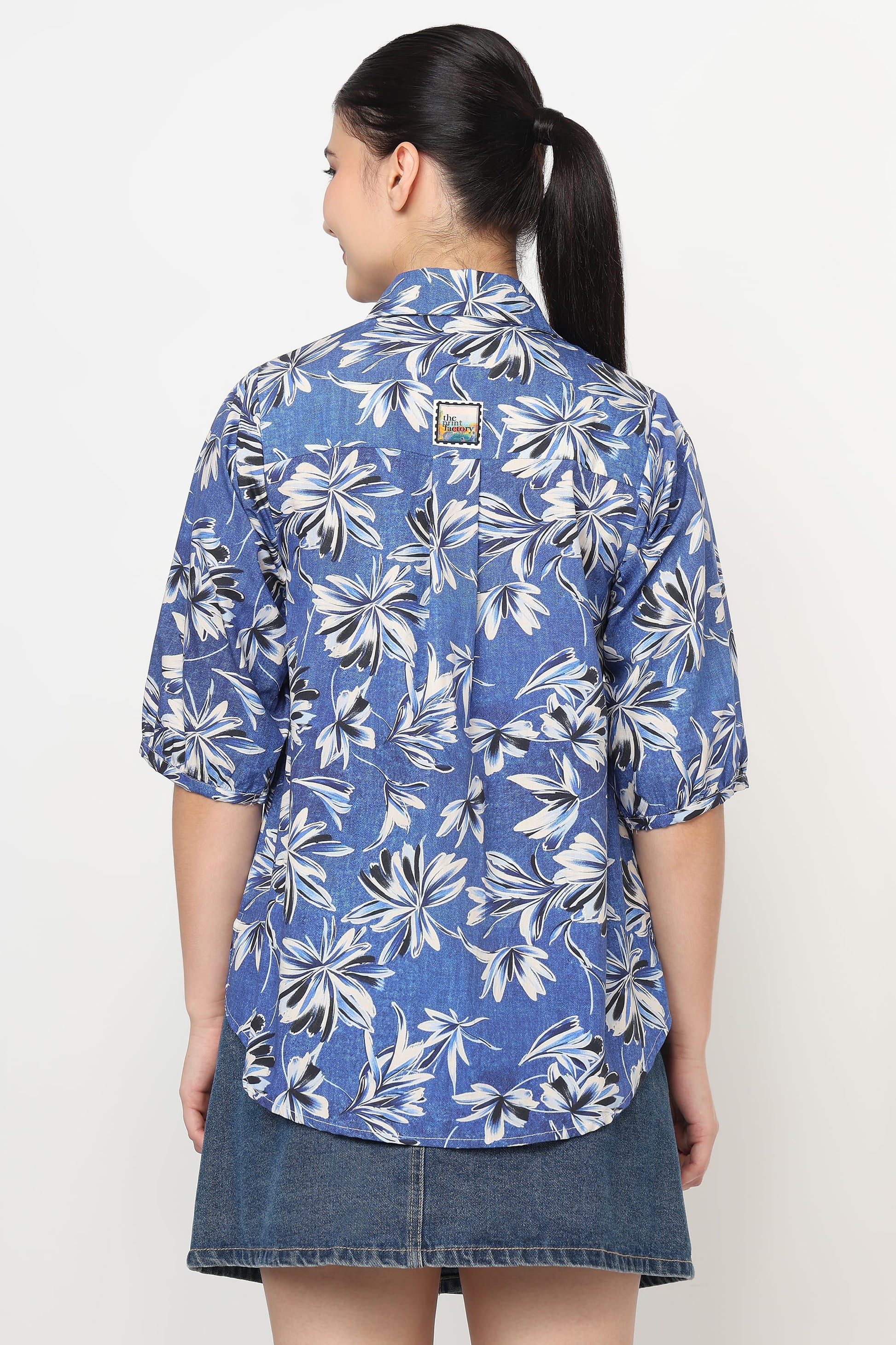 Woman wearing a blue floral patterned shirt on a white background