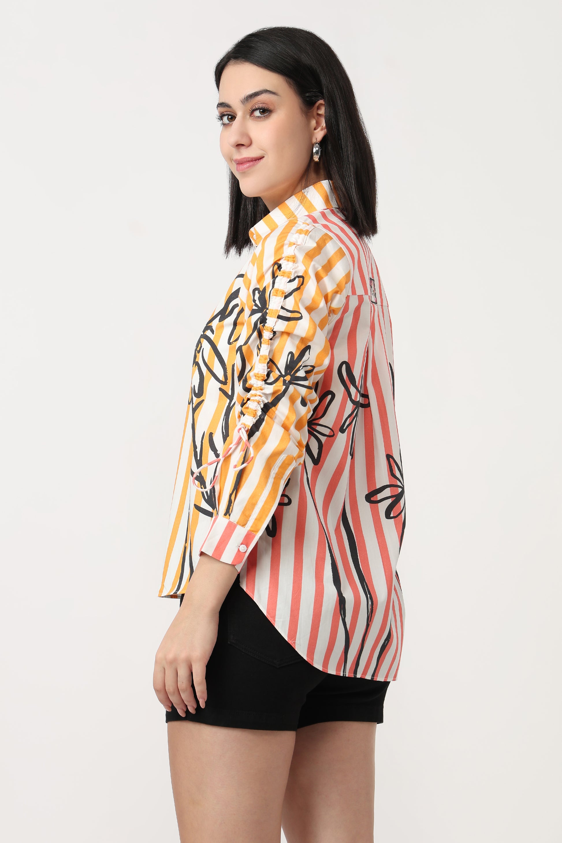 Woman wearing a colorful striped shirt with black floral patterns on a white background