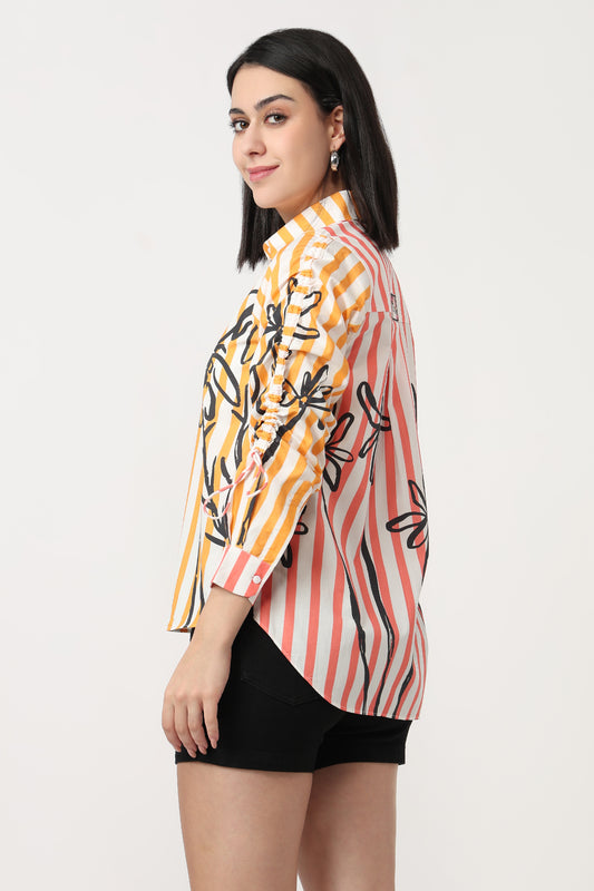 Woman wearing a colorful striped shirt with black floral patterns on a white background