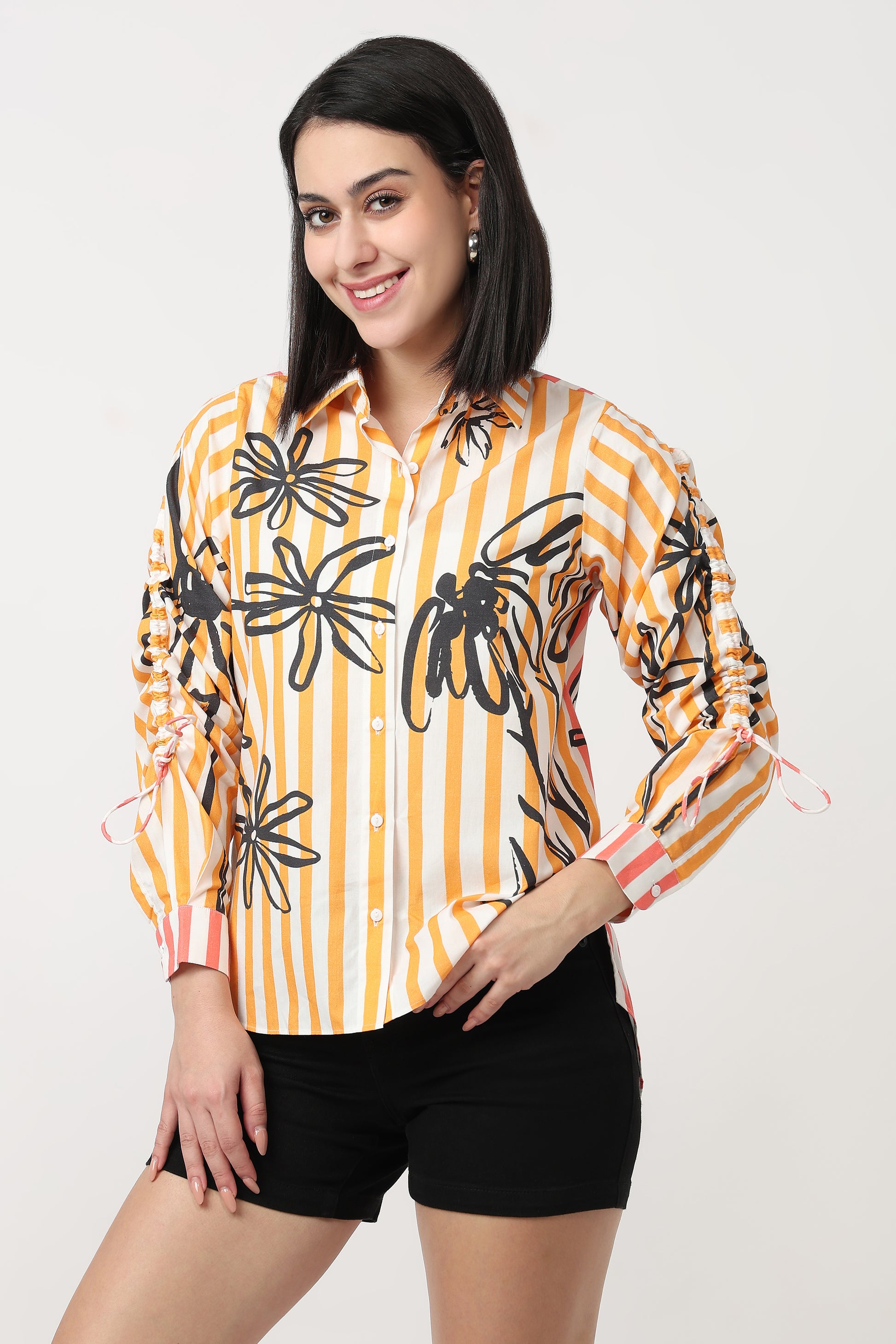 Woman wearing a yellow and black patterned shirt with black shorts on a white background