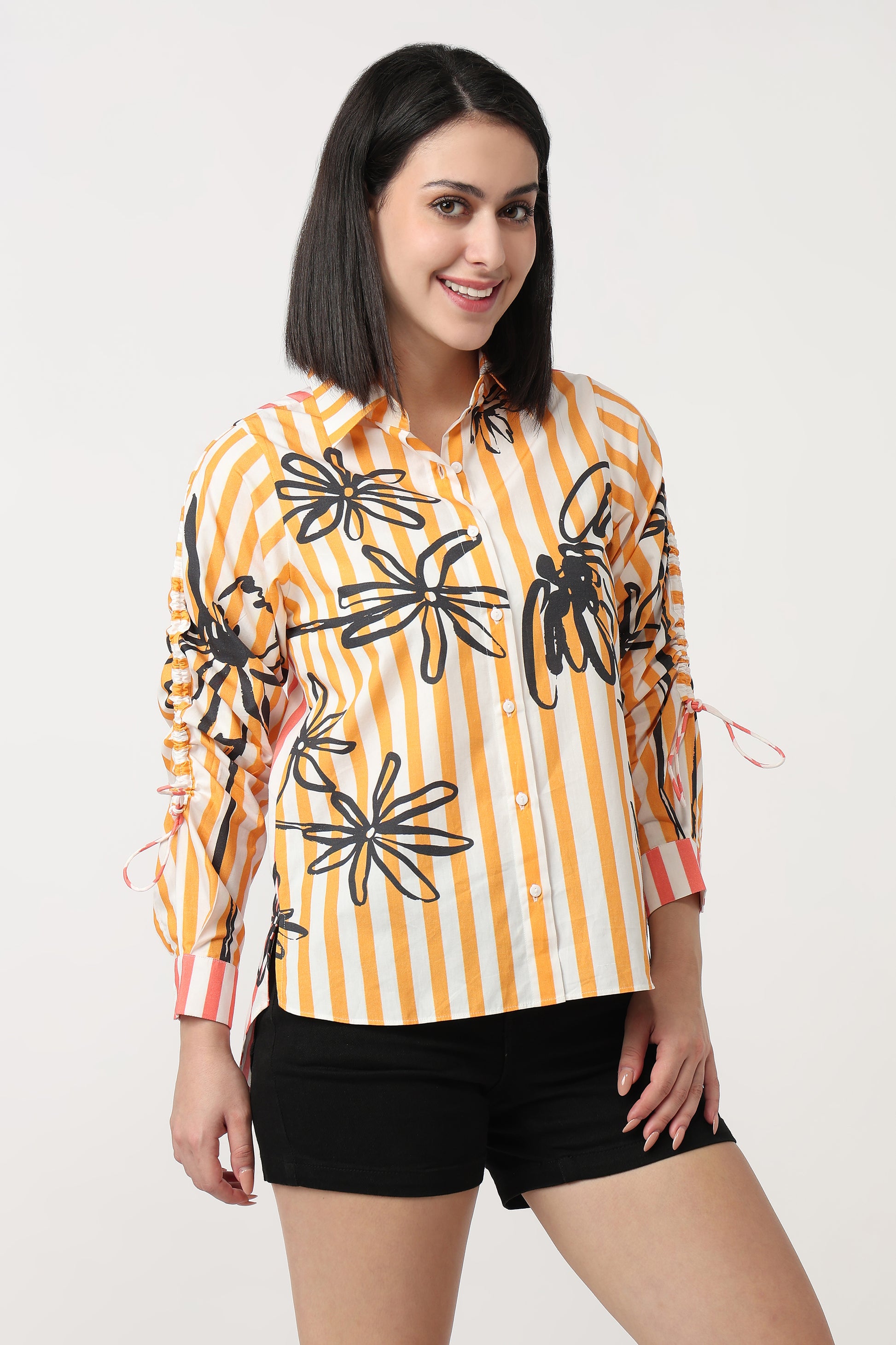 Woman wearing a yellow and orange striped shirt with black floral patterns on a white background
