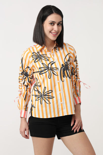 Woman wearing a yellow and orange striped shirt with black floral patterns on a white background