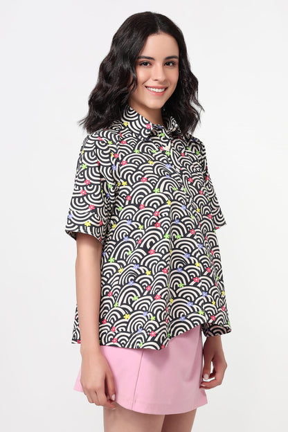 Woman wearing a patterned shirt and pink skirt on a white background