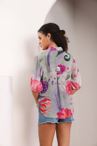 Woman wearing a floral kimono-style shirt against a white wall