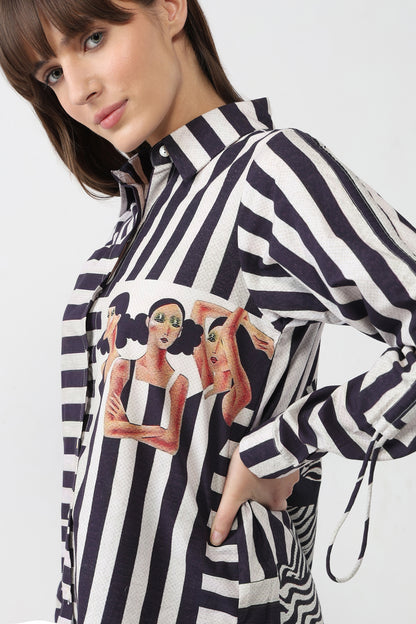 Woman wearing a black and white striped shirt with artistic designs on a plain background