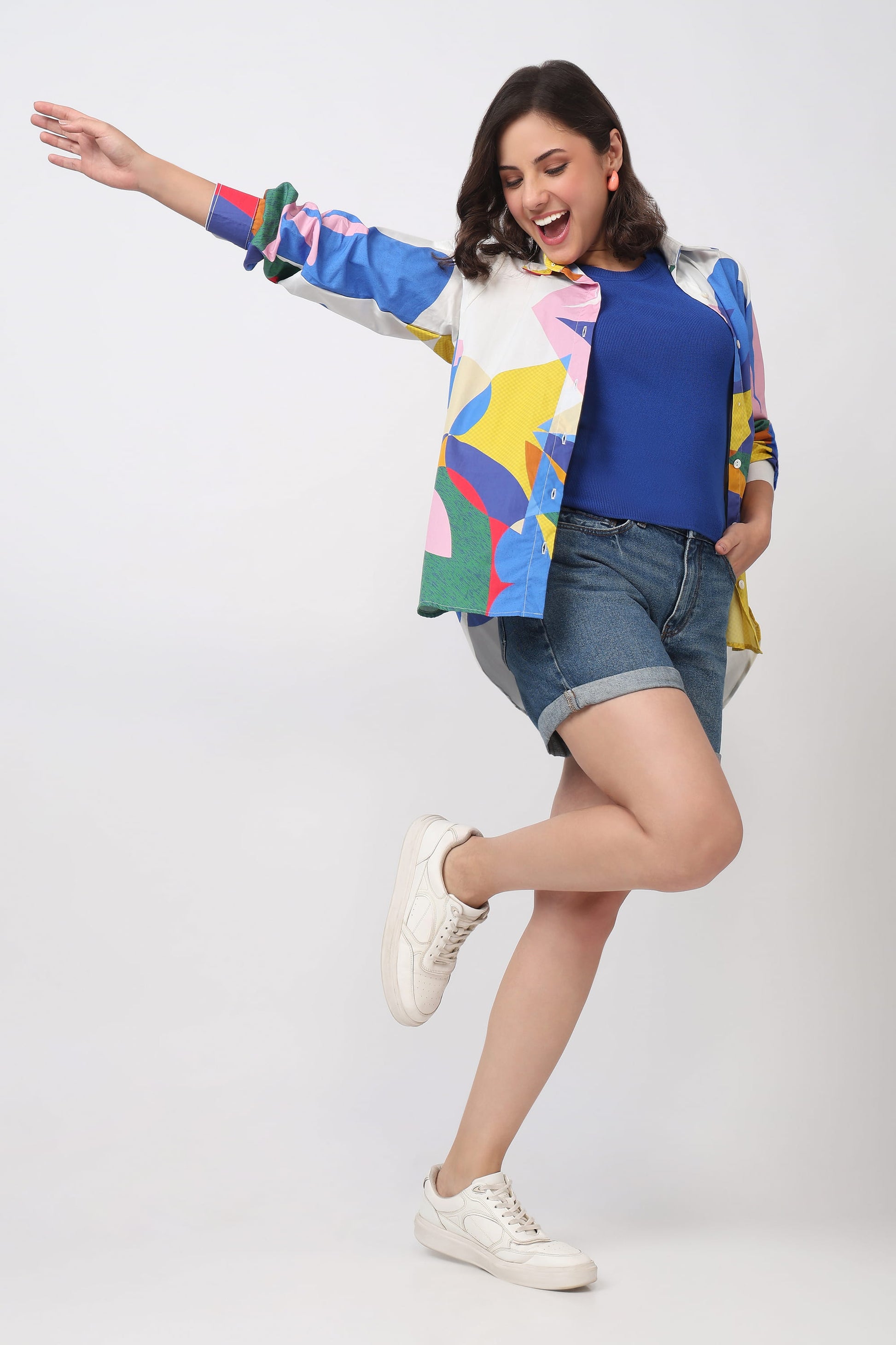 Woman wearing a colorful jacket and denim shorts on a white background