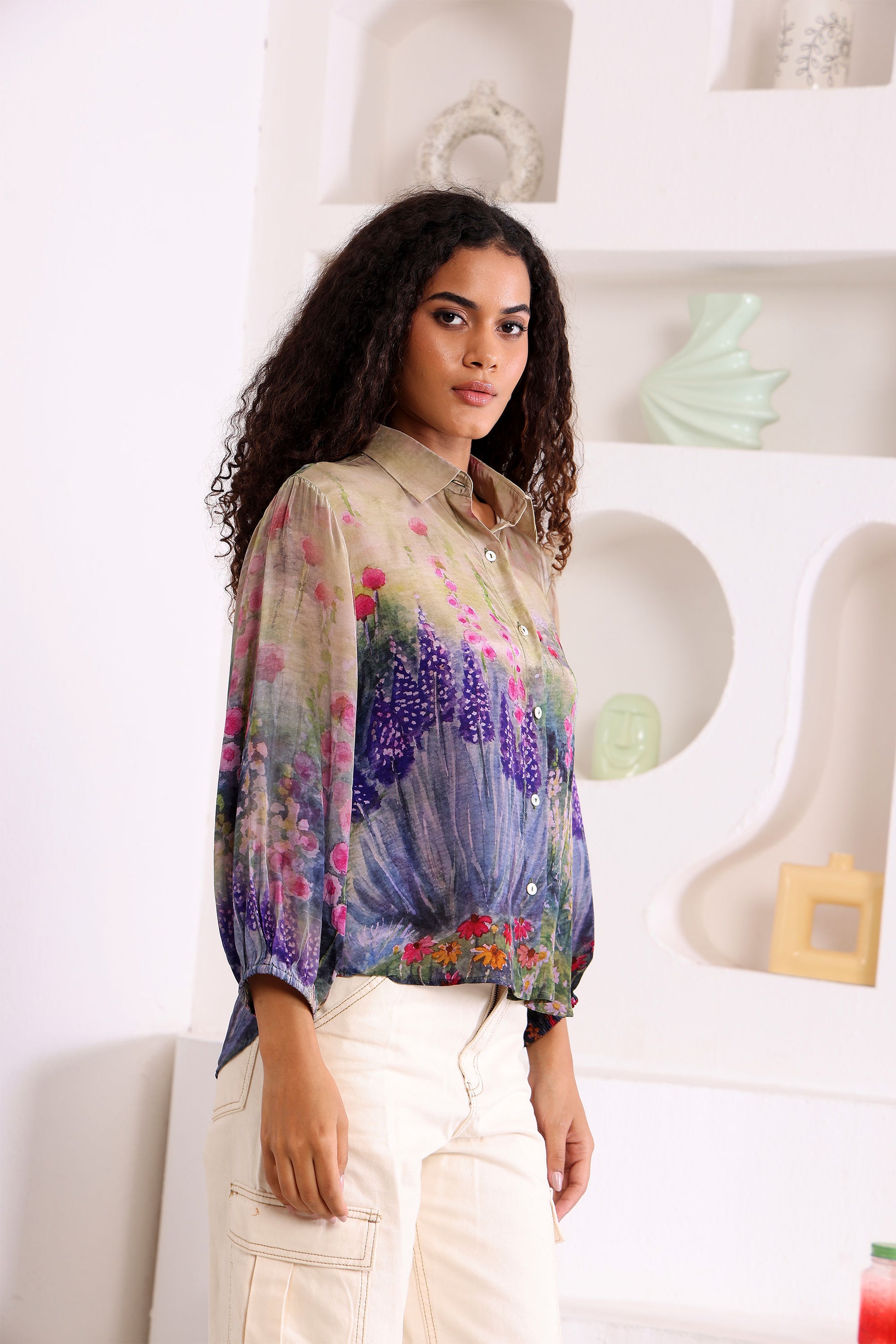 Woman wearing a colorful floral blouse in a minimal indoor setting