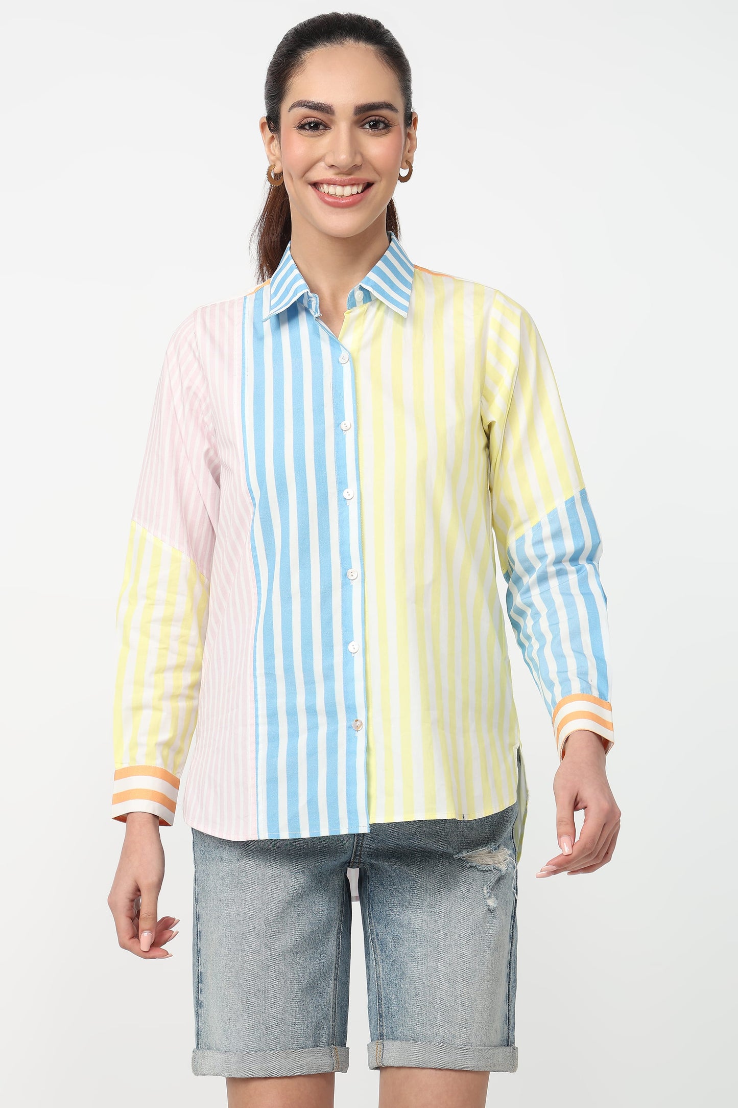 Woman wearing a colorful striped shirt and denim shorts on a white background
