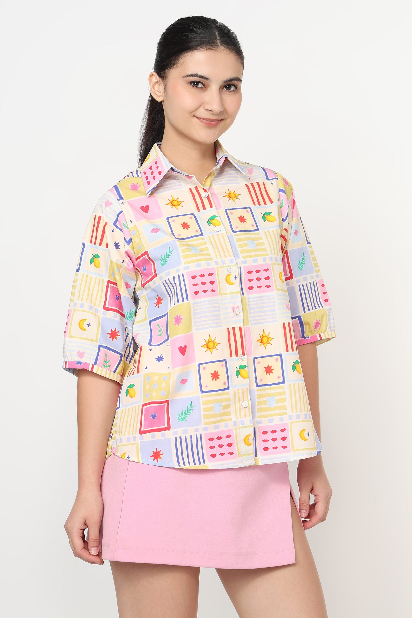 Woman wearing a colorful patterned shirt and pink skirt on a white background