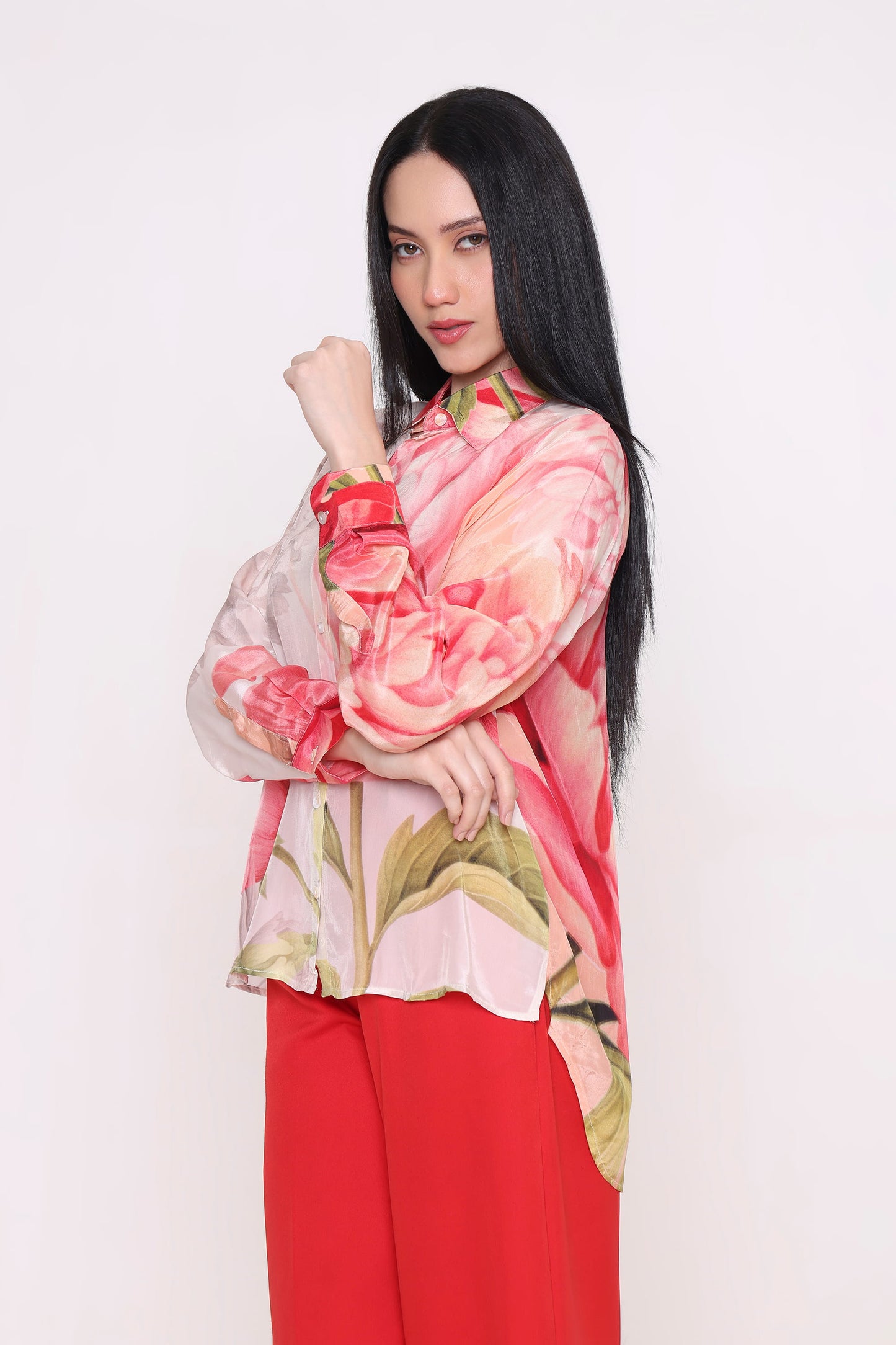 Woman wearing a floral shirt and red pants against a white background