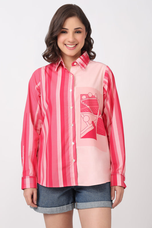 A woman modeling a pink and red striped button-up shirt with a graphic print pocket, paired with denim shorts, against a light gray background.