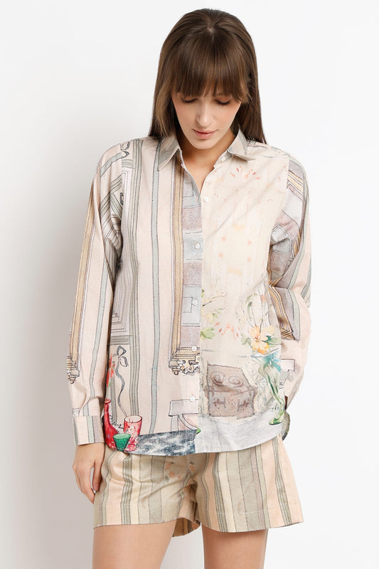A woman modeling a matching two-piece lounge set featuring a long-sleeve button-up shirt and shorts in a beige and cream patchwork print with subtle illustrations.